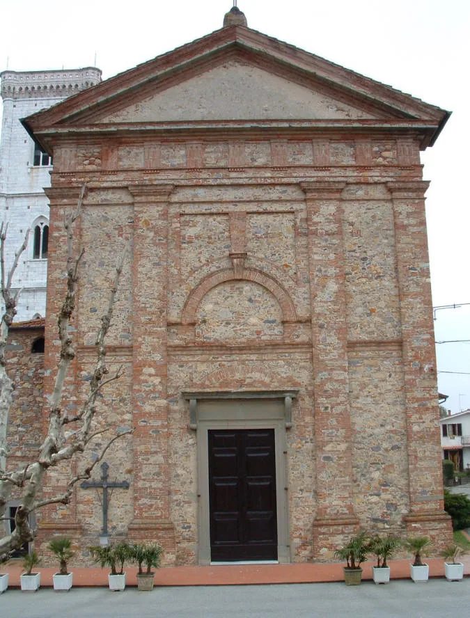 Facciata neoclassica della chiesa di San Lorenzo a Orentano in pietra e mattoni, con timpano triangolare e portone in legno scuro; a sinistra si intravede il campanile