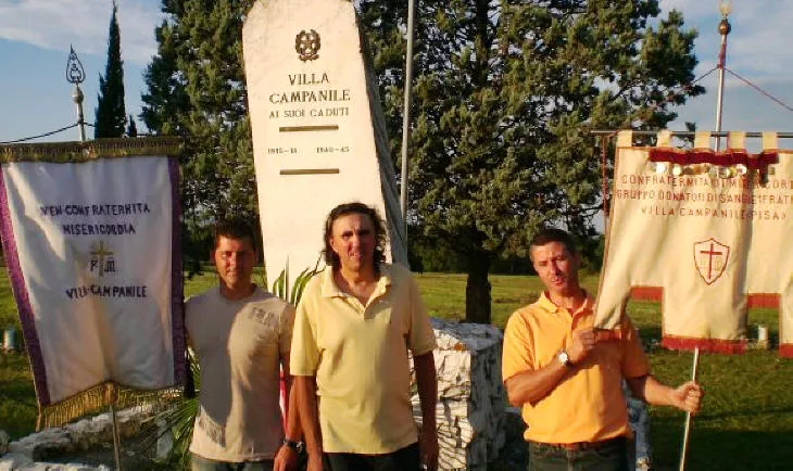 Tre uomini davanti al monumento «Villa Campanile ai suoi caduti» con gli stendardi della Confraternita di Misericordia e del gruppo donatori di sangue Fratres di Villa Campanile