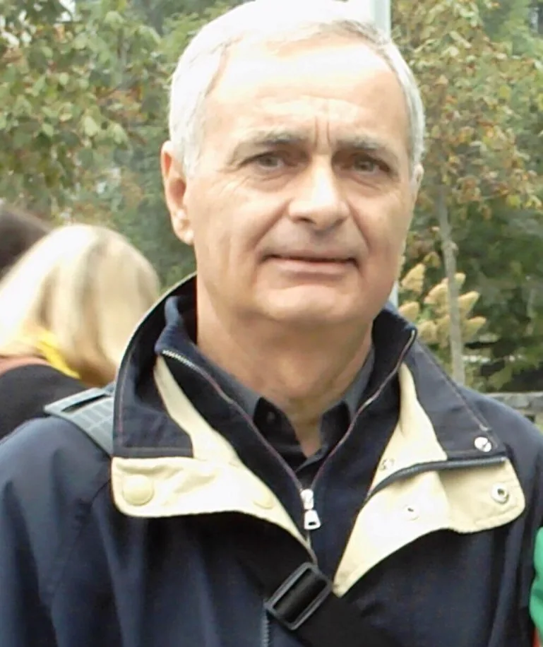 Ritratto all’aperto del diacono Roberto Agrumi, capelli bianchi, giacca blu con colletto beige