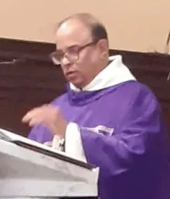 Padre Ivan Clifford Pinto, con occhiali e casula viola, predica dall’ambone