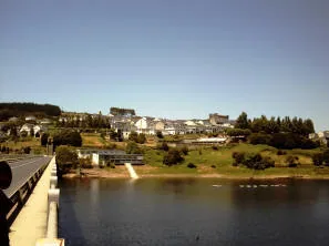 Case bianche su una collina affacciata su un bacino d'acqua, viste da un lungo ponte