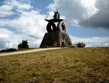 Il grande monumento in metallo sul Monte del Gozo, in cima a una collina erbosa, sotto un cielo con nuvole