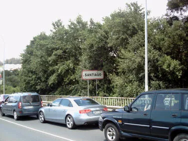 Cartello stradale con la scritta Santiago lungo una strada con automobili in coda