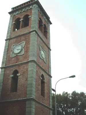 Il campanile di Villa Campanile visto dal basso: torre in mattoni con cornici in pietra, bifore della cella campanaria e quadranti dell’orologio a forma di quadrifoglio